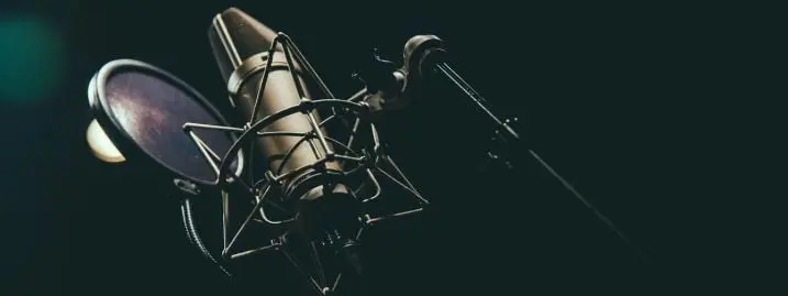 condenser-microphone u87 microphone behind black background with popfilter