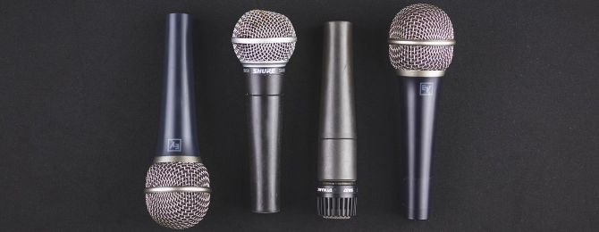 various dynamic microphones lined up beside eachother on a black background